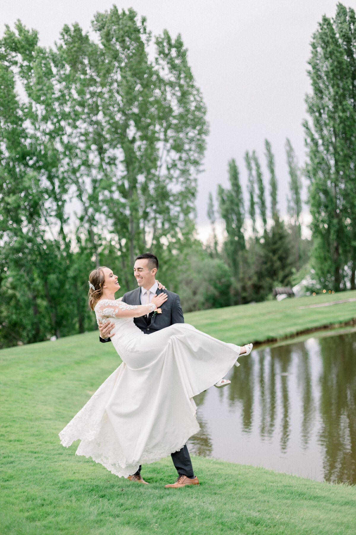 Bride and groom spinning and laughing by a  pond on their wedding day taken by washington wedding photographer