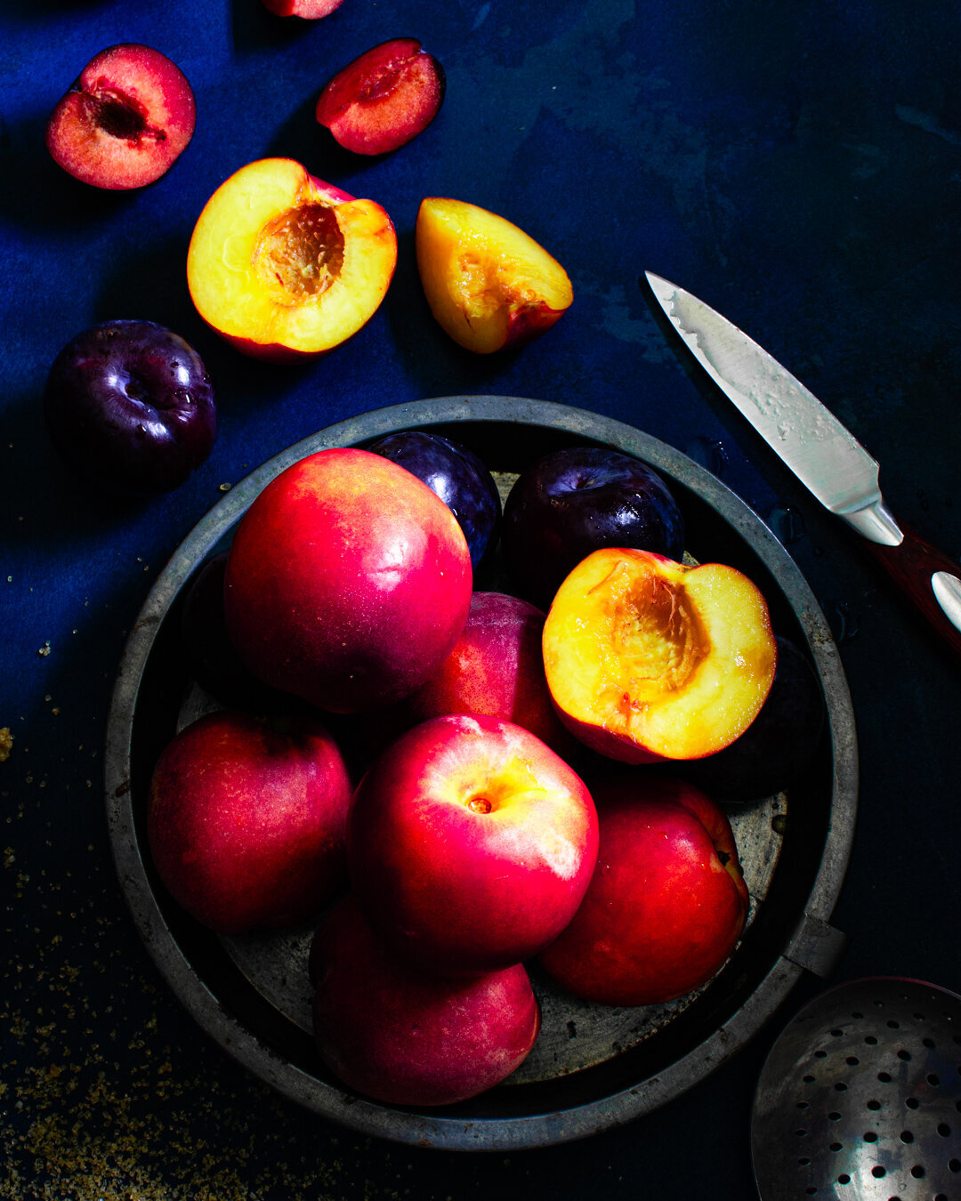 Nectarines and plums in a bowl with a knife