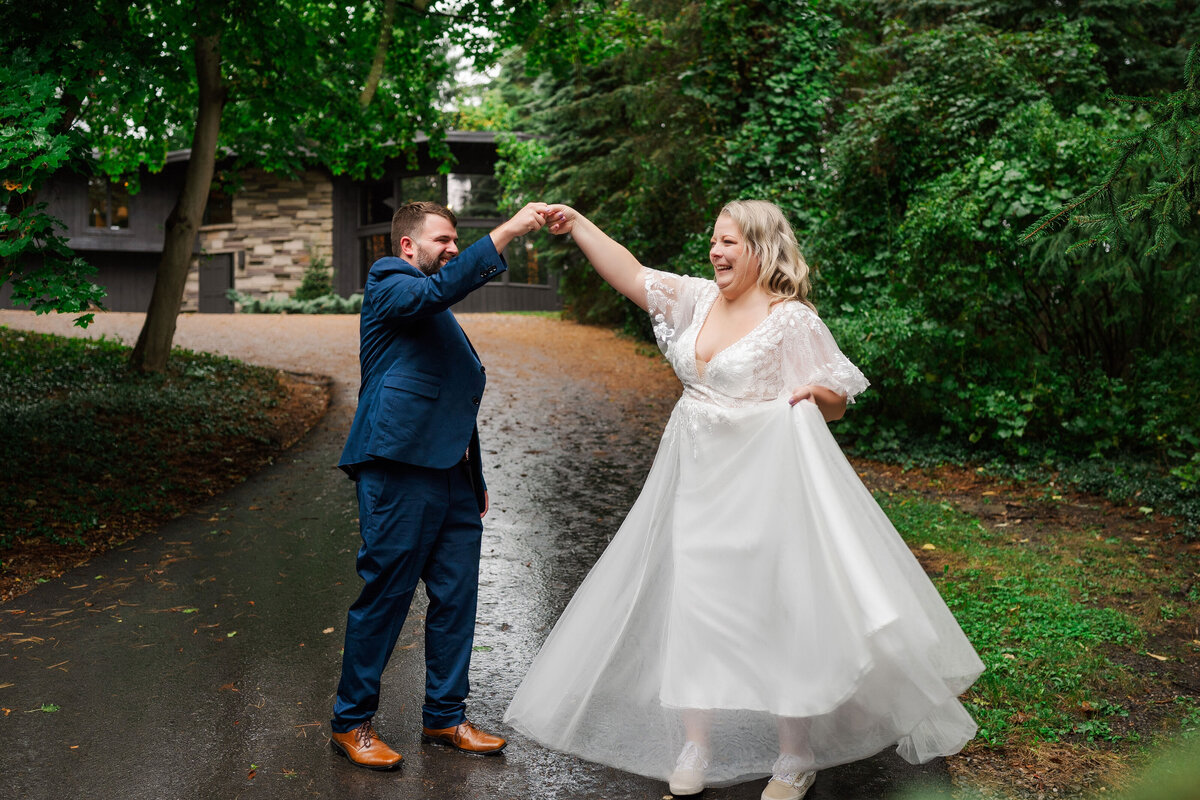 couple having fun and twirling in the rain on their wedding day