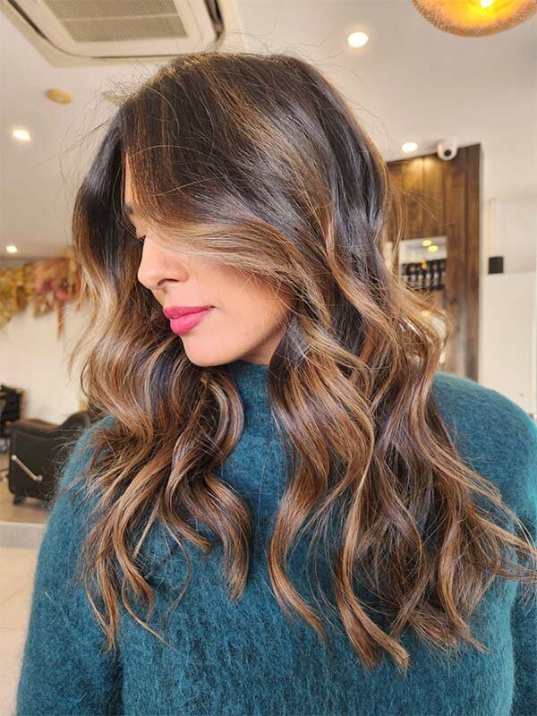 Glossy brunette hair with warm highlights styled in loose curls, representing full-colour hair services at Blake & Kwan Hair Salon.
