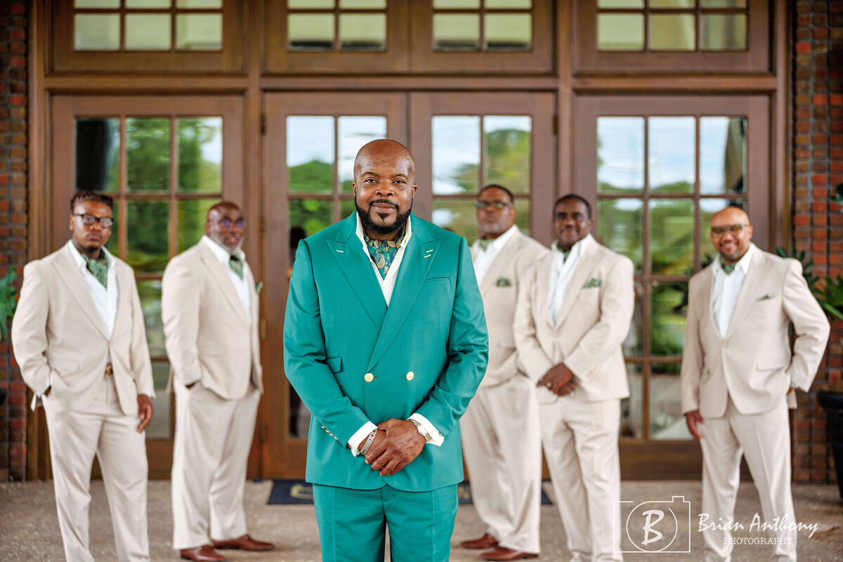 Stylish groom in an emerald green suit standing with his groomsmen before the ceremony.