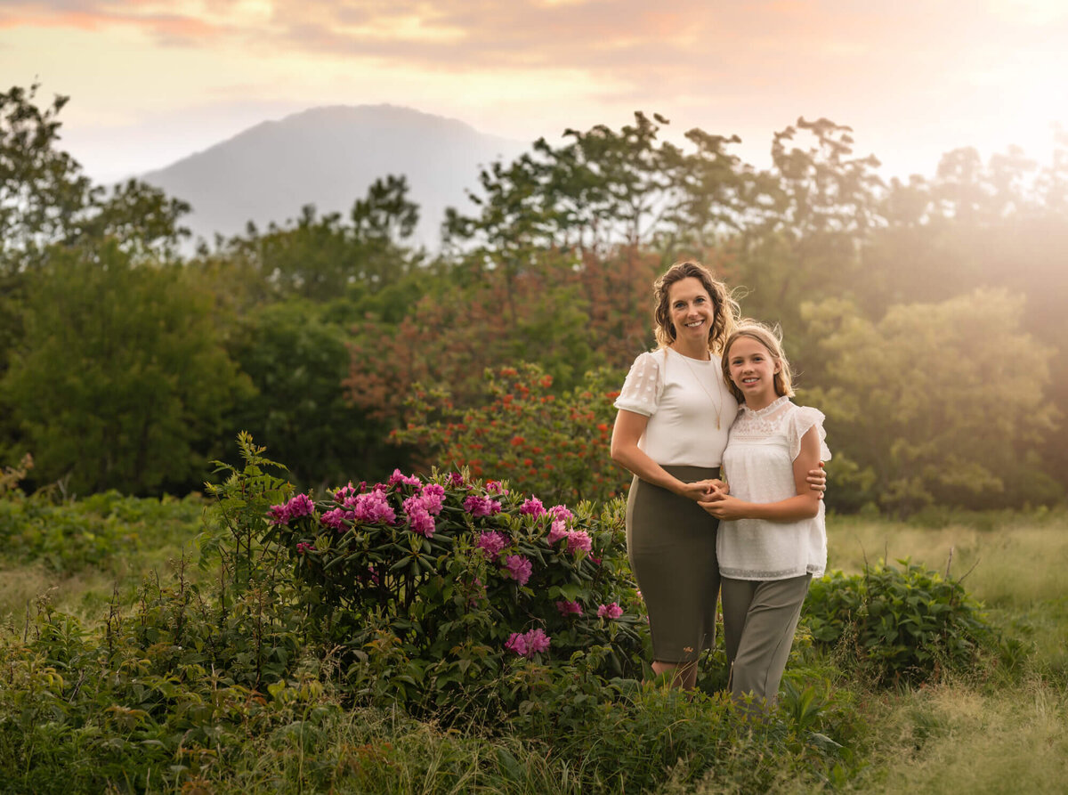 A beautiful mom and daughter hugging  while standing near the wild flowers at Craggy Gardens