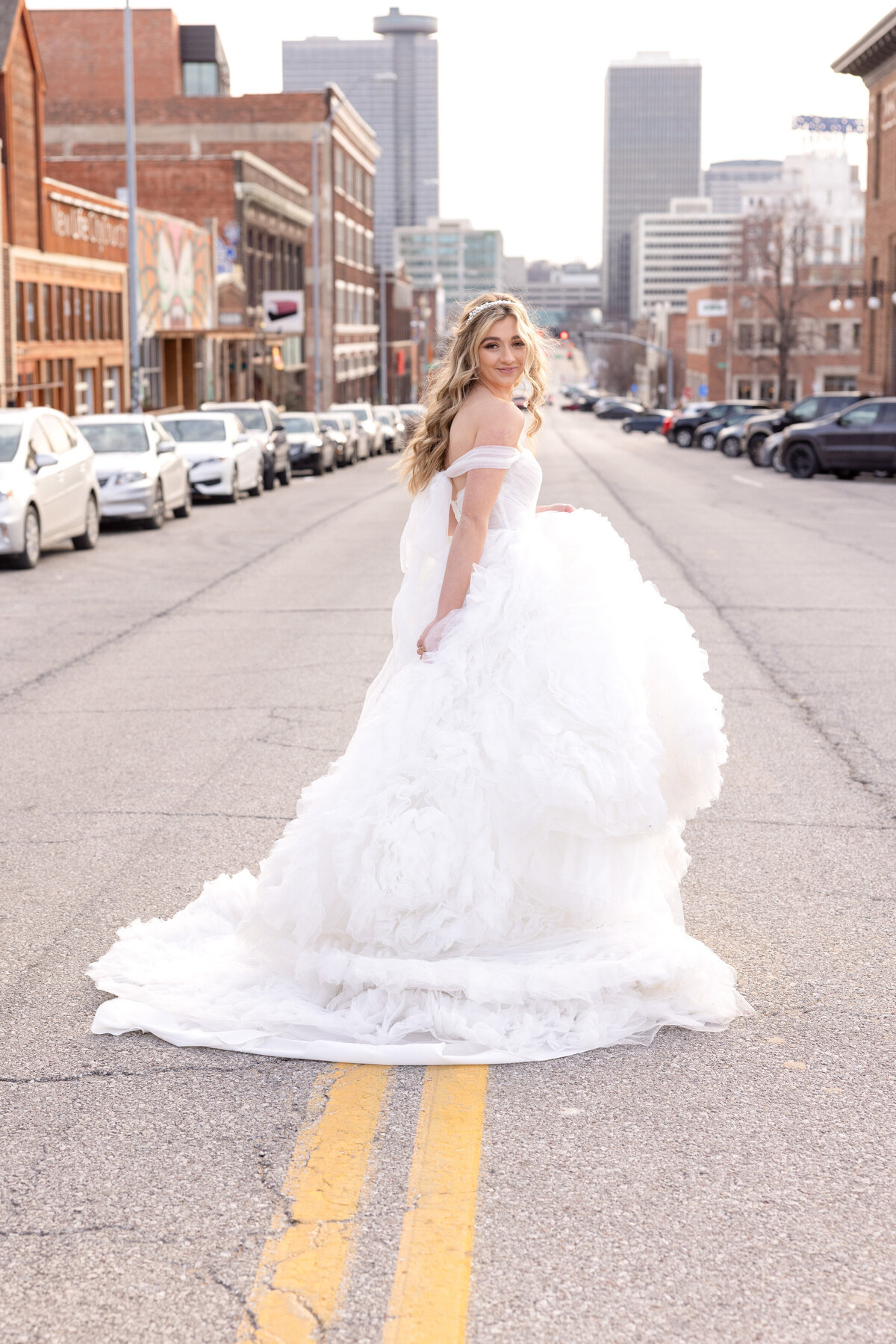 bride with off the shoulder dress with plumes walking across street