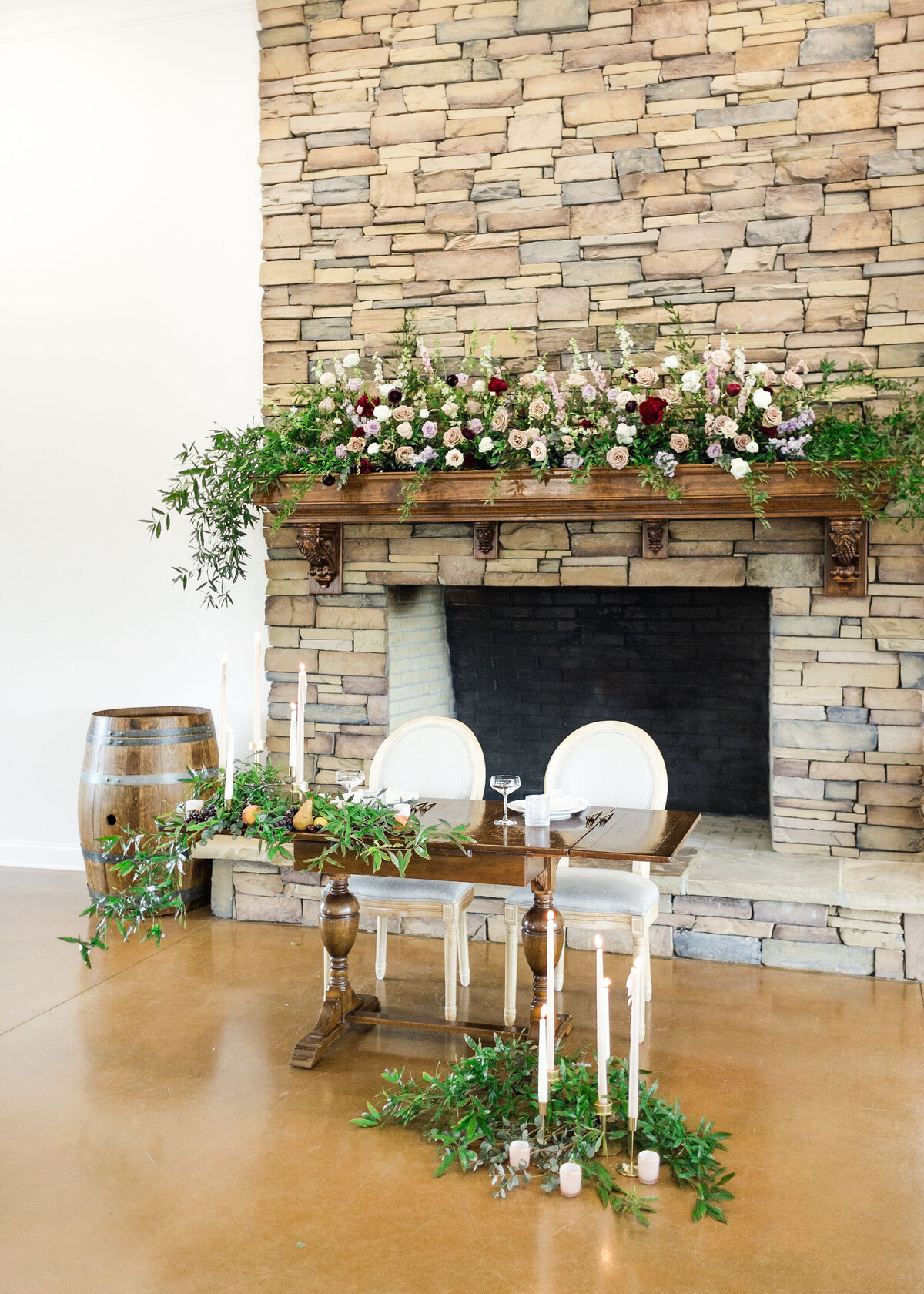 A stone fireplace with vibrant floral arrangements, creating a romantic and elegant backdrop for weddings and events at Willow and Stone Events near Charlotte, NC.