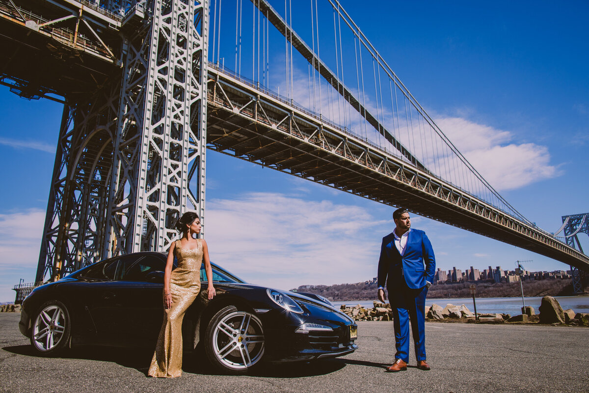 An engaged couple standing with a porsche in fort lee historic park near the george washington bridge in nj