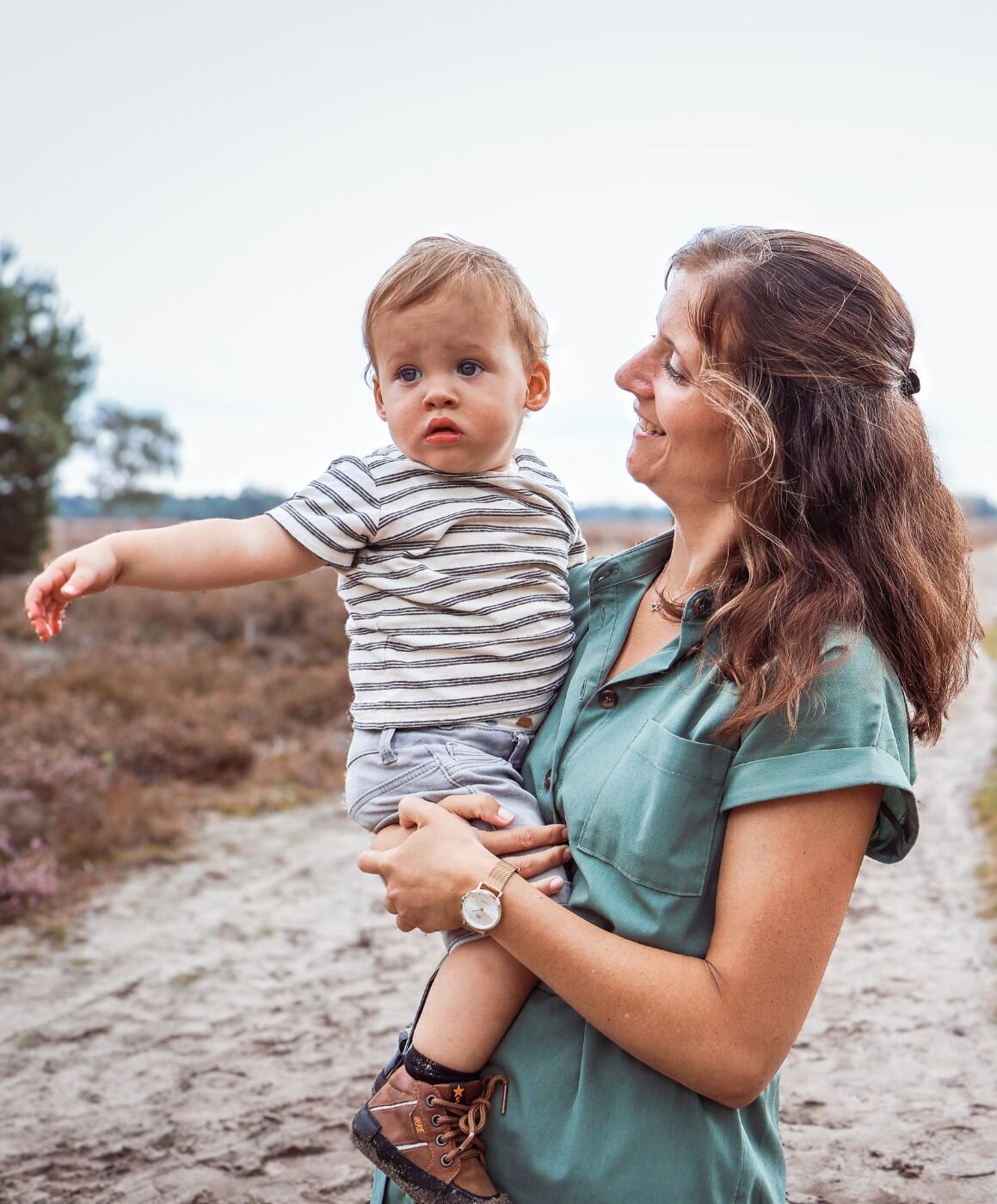 Een vrouw houdt een baby vast in een veld met lang gras.