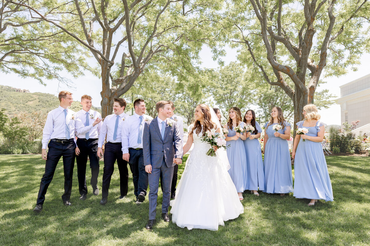 The newlyweds walk hand-in-hand through the garden, surrounded by their supportive bridal party.