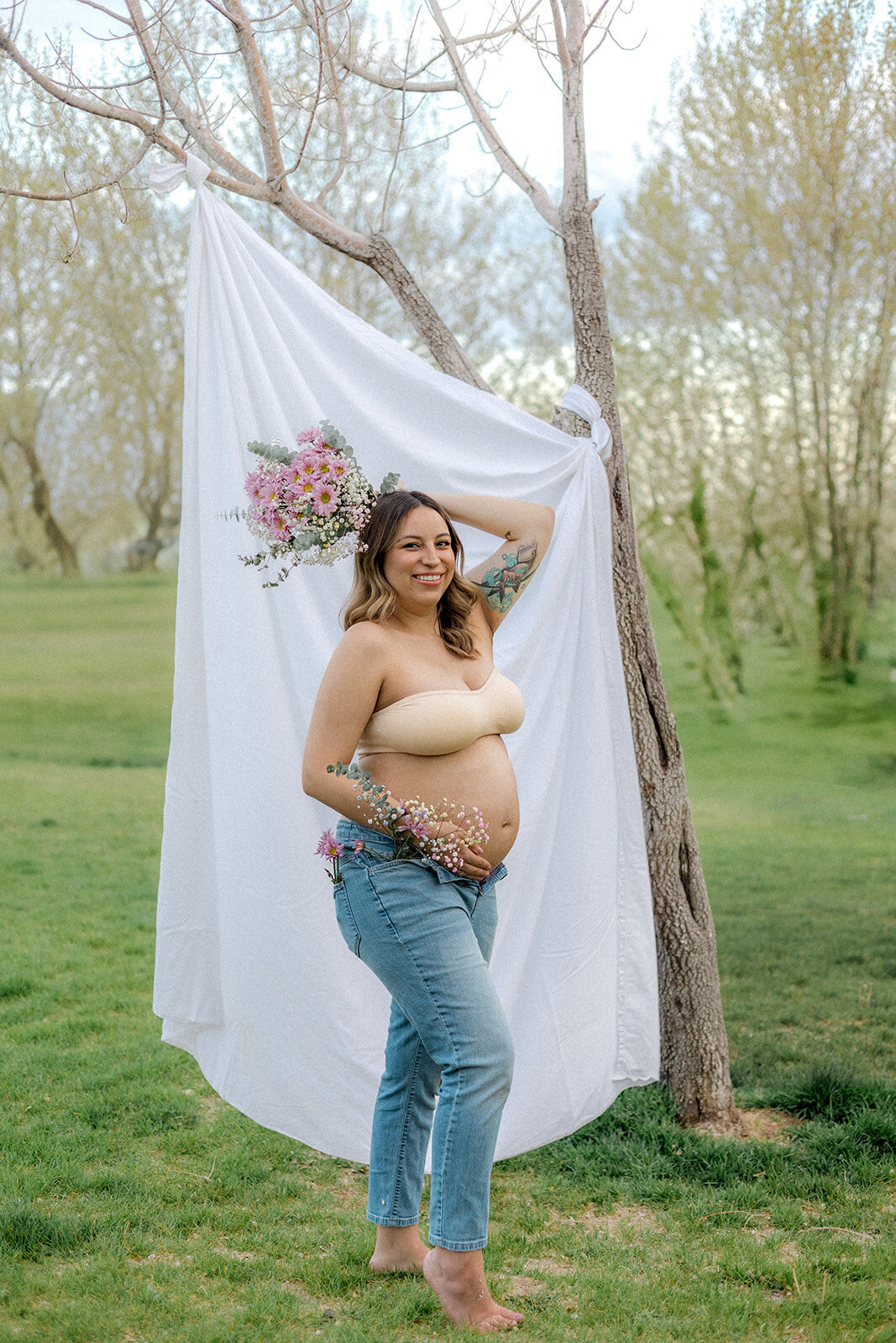 A pregnant woman holds her belly while holding flowers