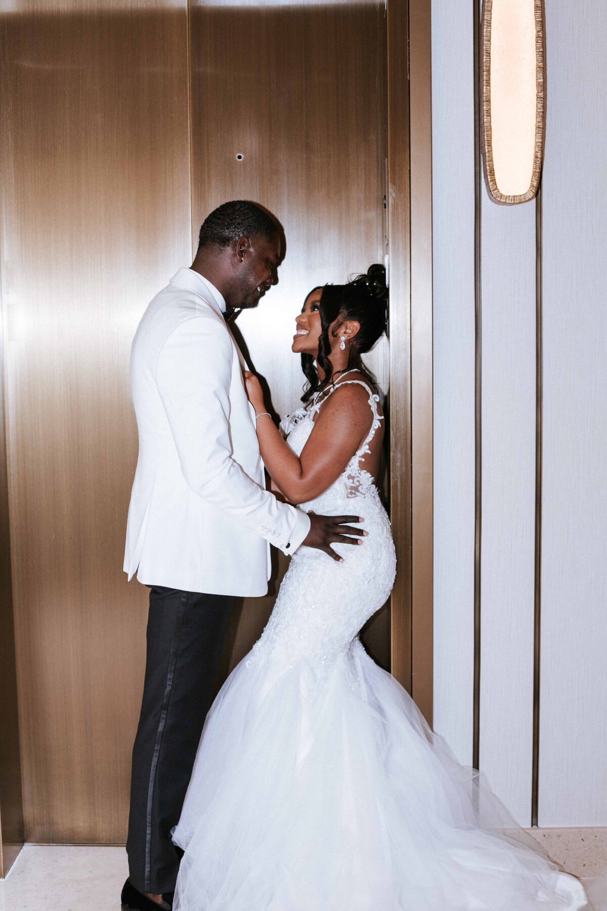 Captured by Phavy Photography, a Jacksonville wedding photographer, this stylish hotel elevator shot features a beautiful Black couple sharing a fun, romantic moment on their wedding day. The bride’s fitted lace gown and the groom’s white tux create a sleek, modern look. Phavy’s editorial eye and documentary approach make this a timeless image full of personality and connection.