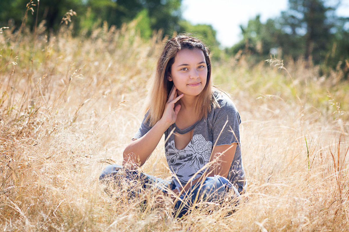 High school senior girl in a skull t-shirt sits in a field