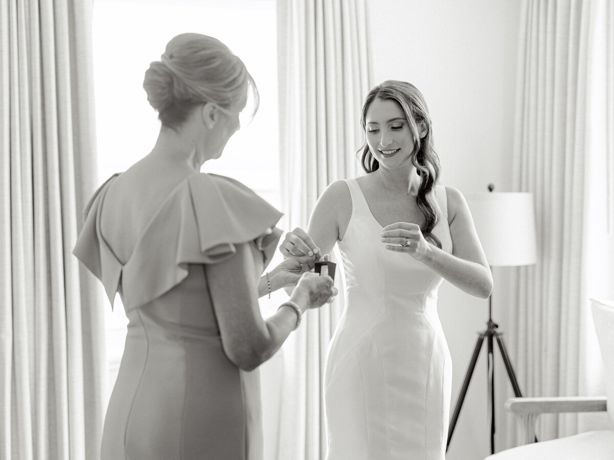 Black and white photo of mom handing bride perfume