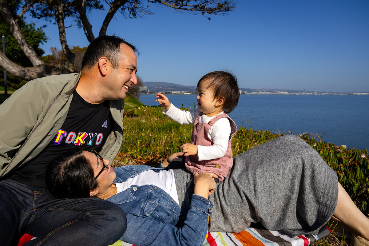 Candid moment of parents and toddler bonding by the San Francisco Bay – natural light family photography by Ellobelle Photography, San Francisco Peninsula Bay Trail Burlingame
