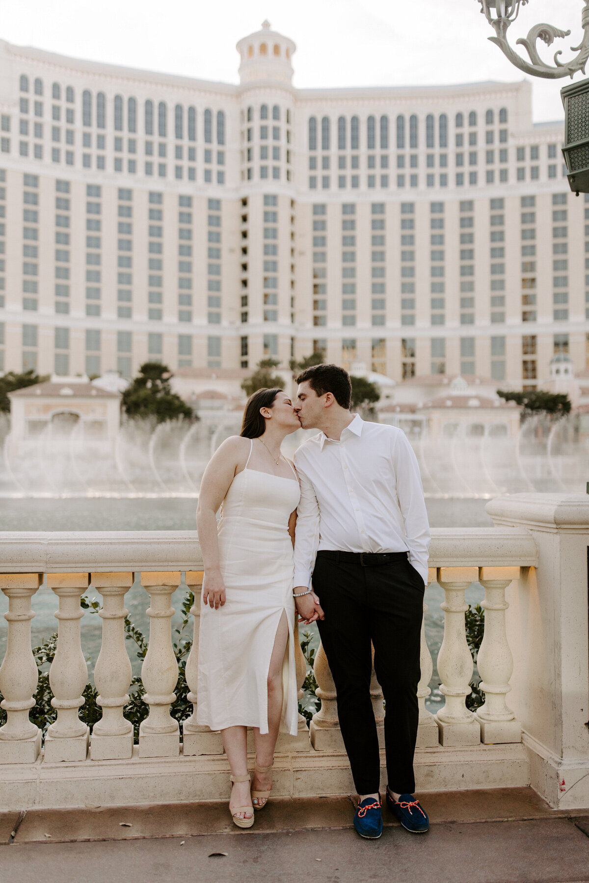 Partners kiss while the Bellagio fountains go off behind them.