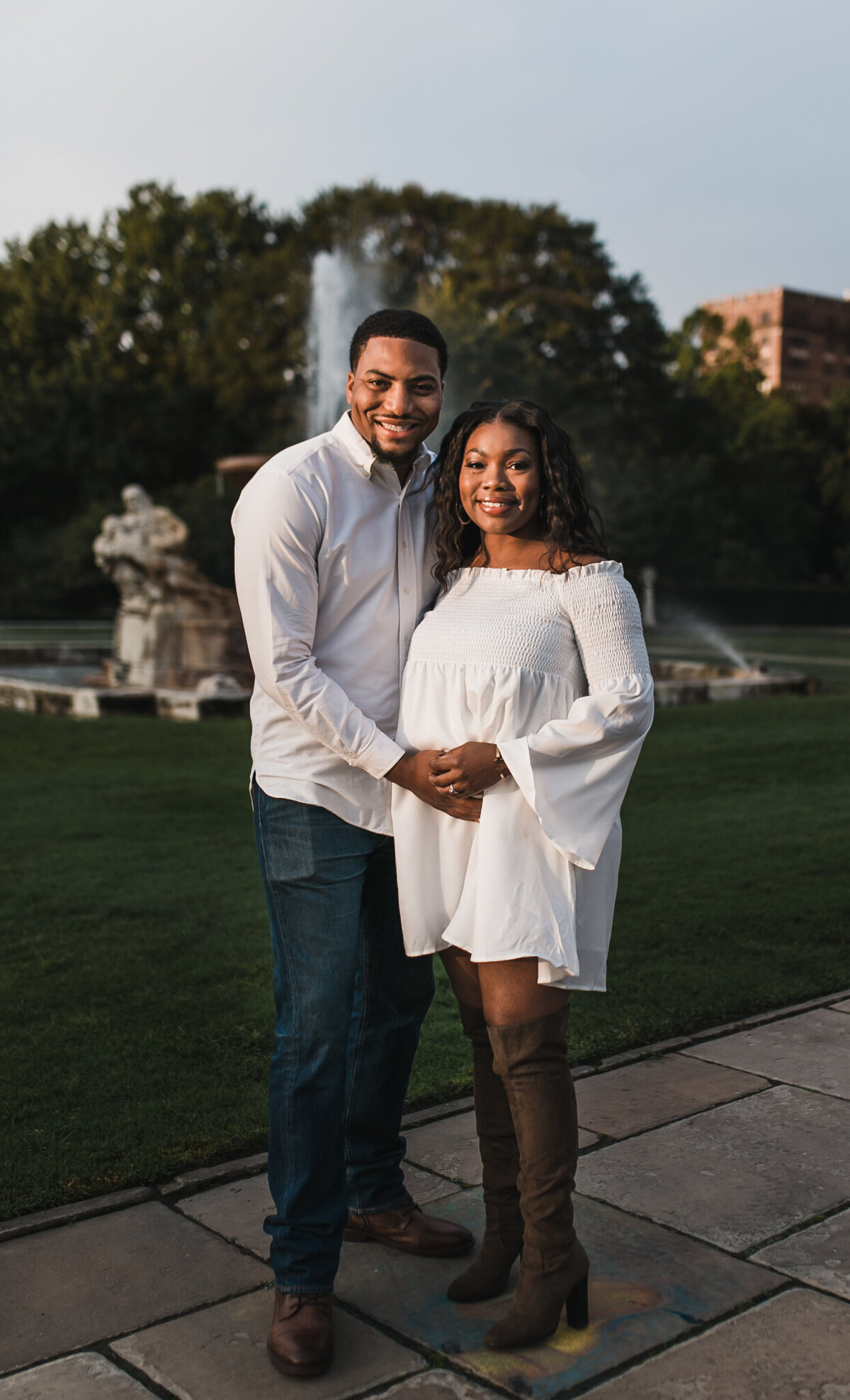 Pregnancy photoshoot with soon to be mom and dad holding hands outside.