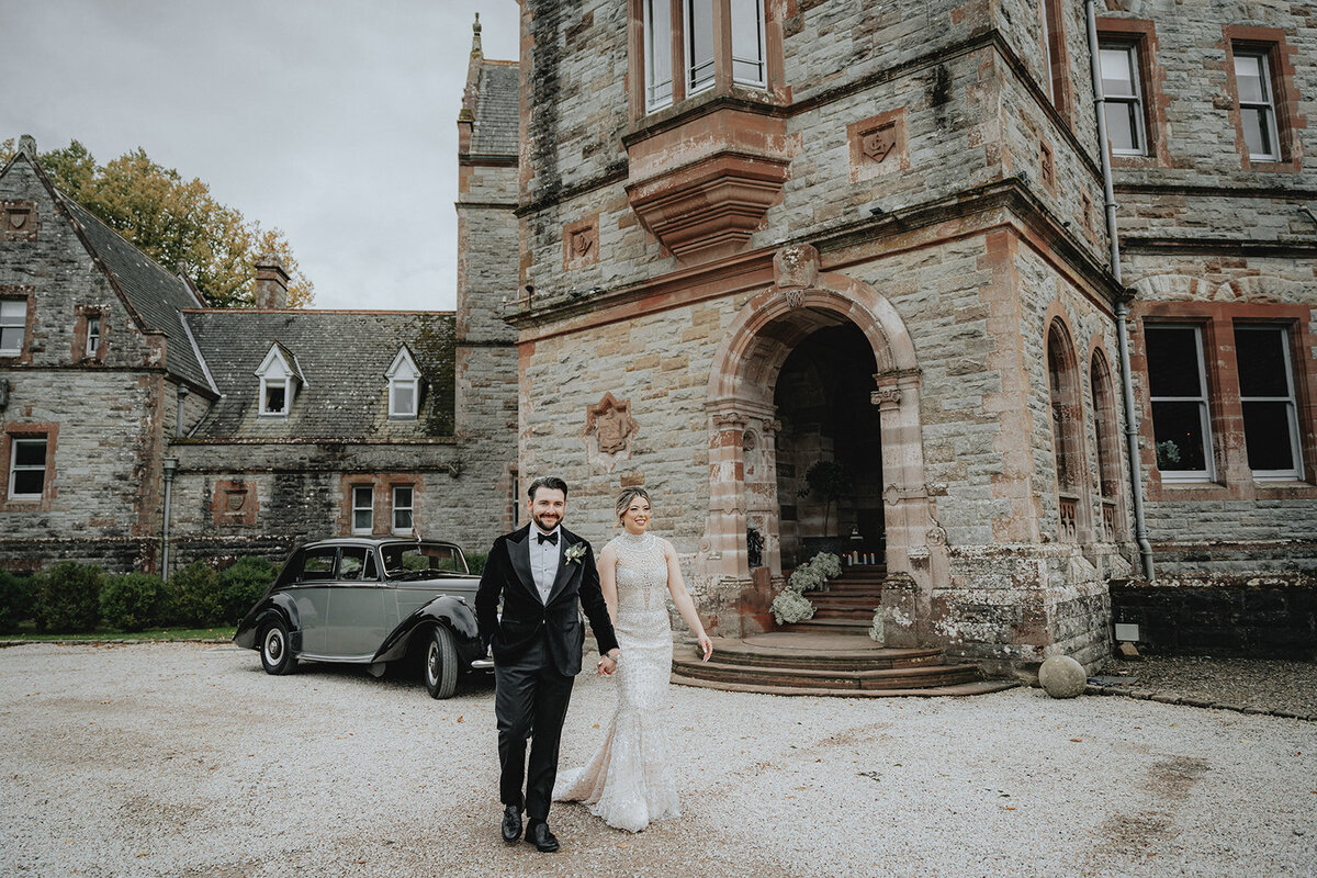 Bride and groom walking with castle in background in Ireland
