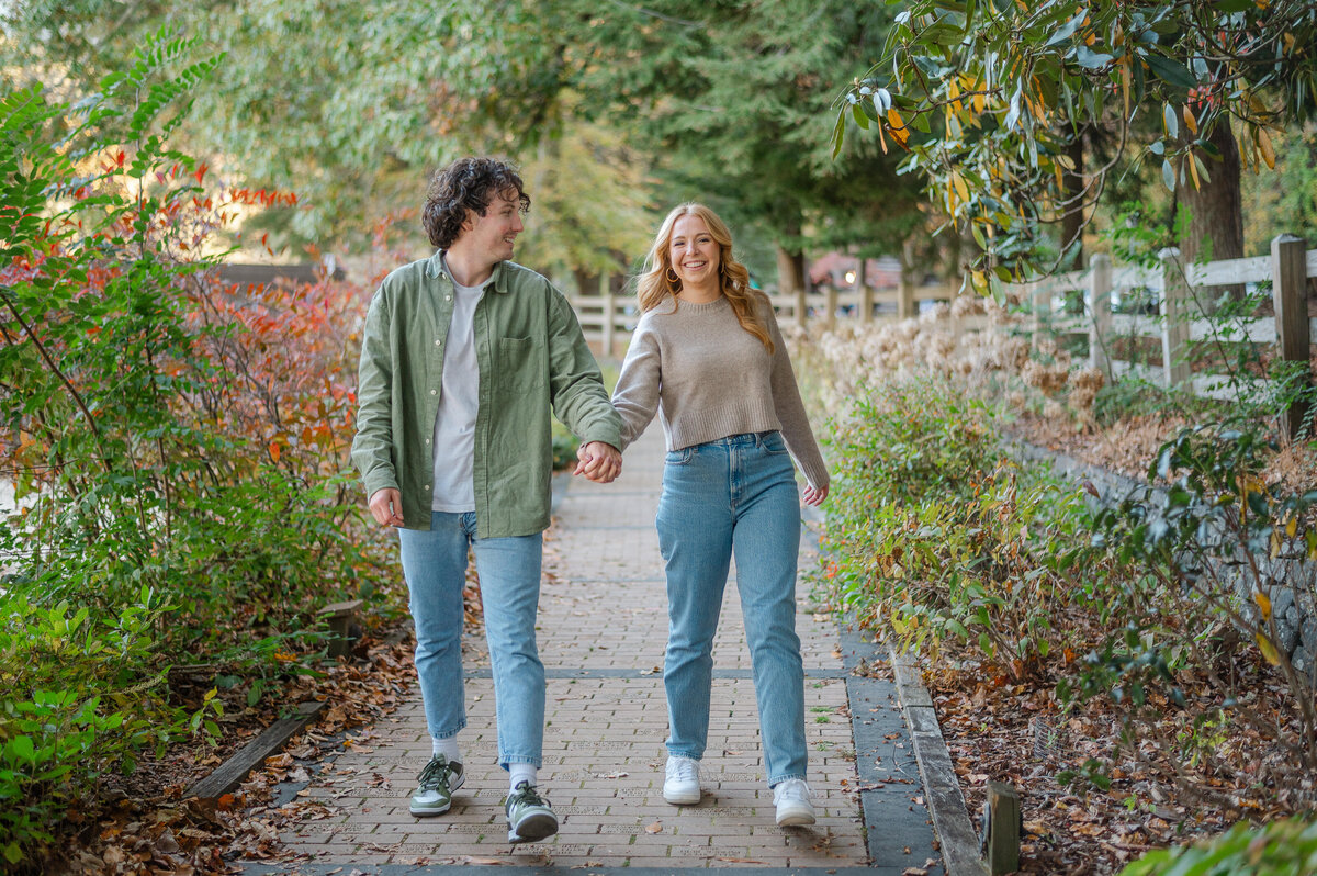 Couple laughing together as they walk hand in hand through Vogel State Park. North Georgia engagement photography by Amanda Touchstone