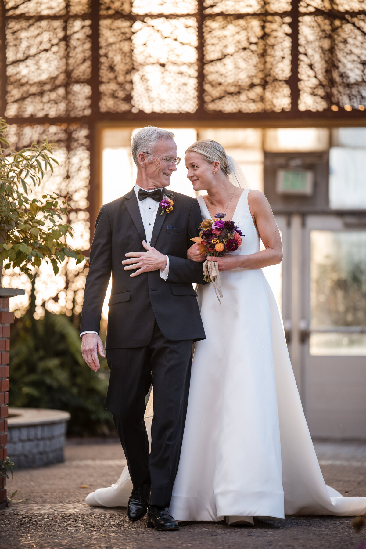 A bride walks down the aisle with her father at a  Fairmount Park Horticulture Center wedding