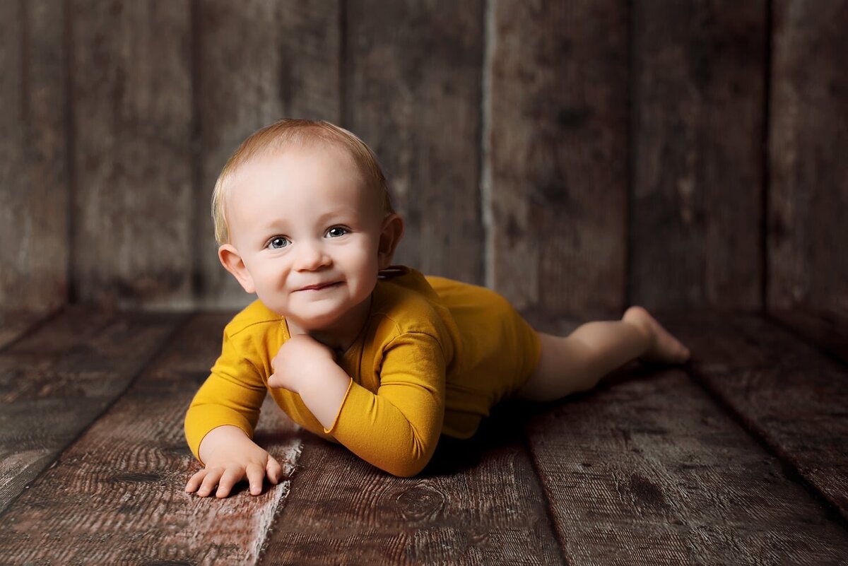 Smiling 1 year old boy in yellow romper for first birthday photo session.