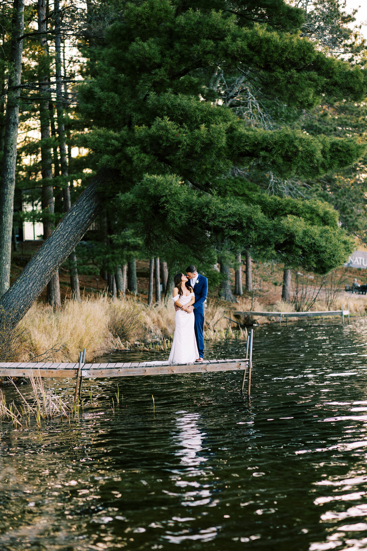 Bride and groom standing on the dock kissing at Catalyst by Nature Link