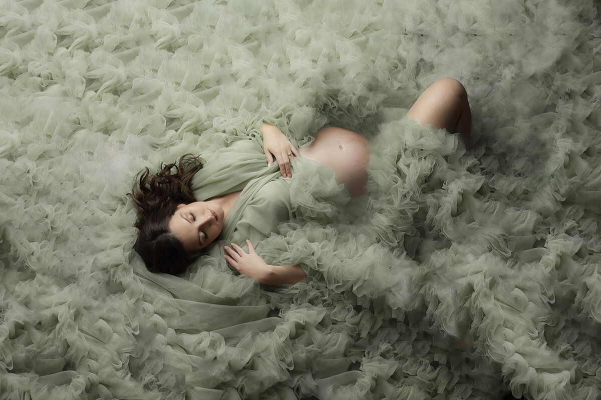 mother laying on green tool holding pregnant belly