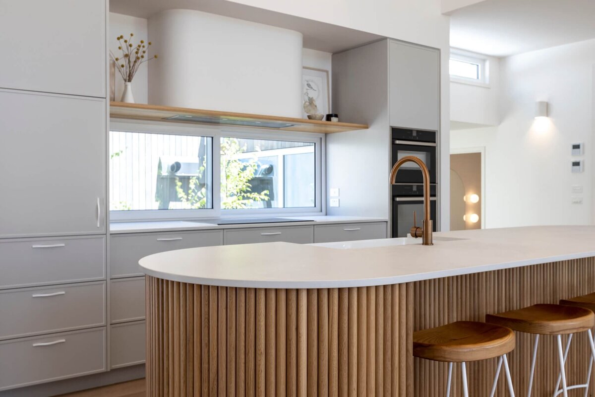 Timber cladded island with stone worktop and grey kitchen cupboards