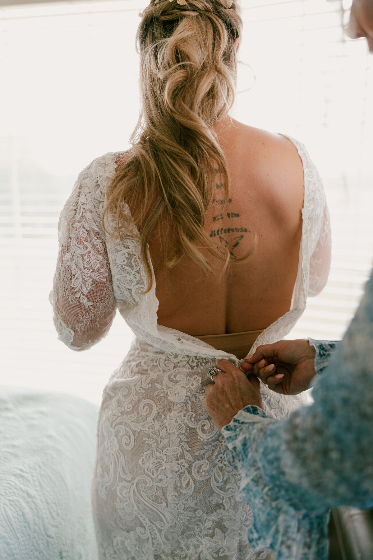 A person helping someone zip on their wedding dress 