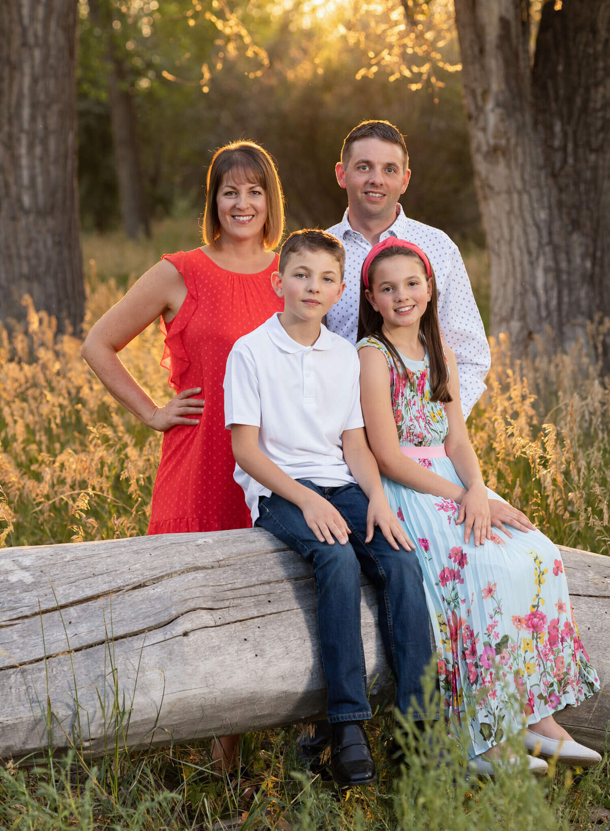 family of four sitting on a log in a field in City Park Pueblo Colorado