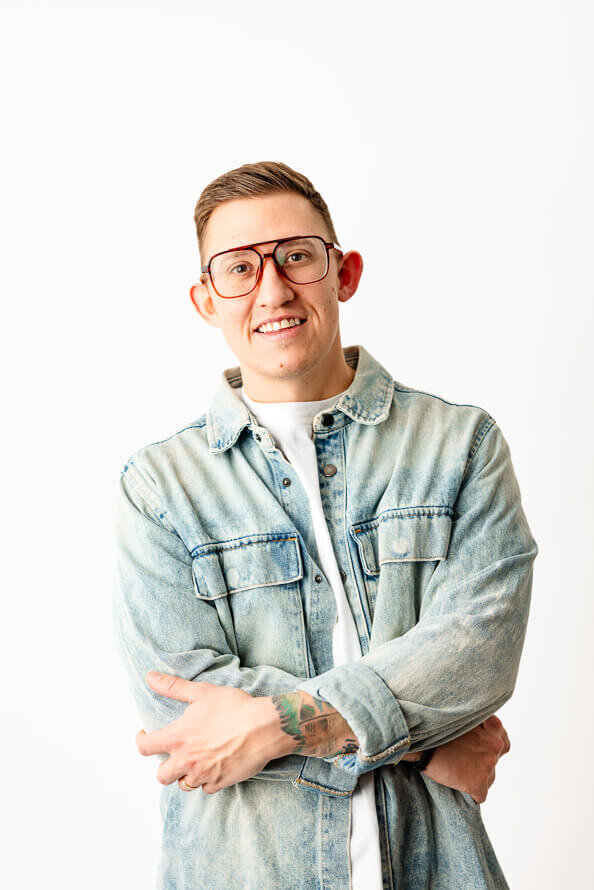 Man folds arms and leans back in a white photos studio.