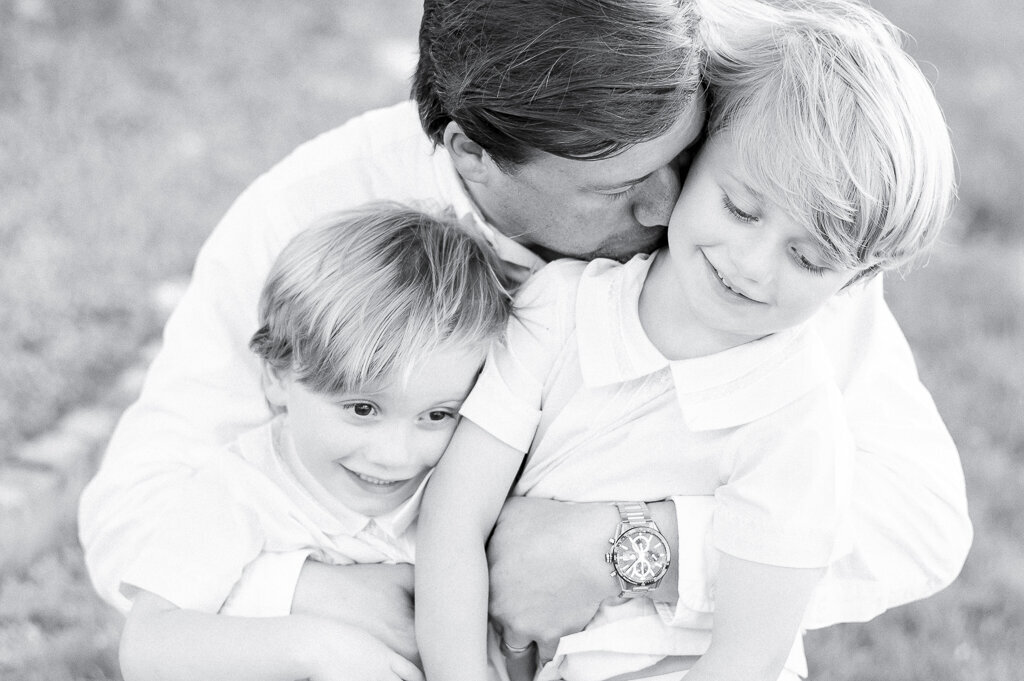 Black and white image of a father and his sons as they hug