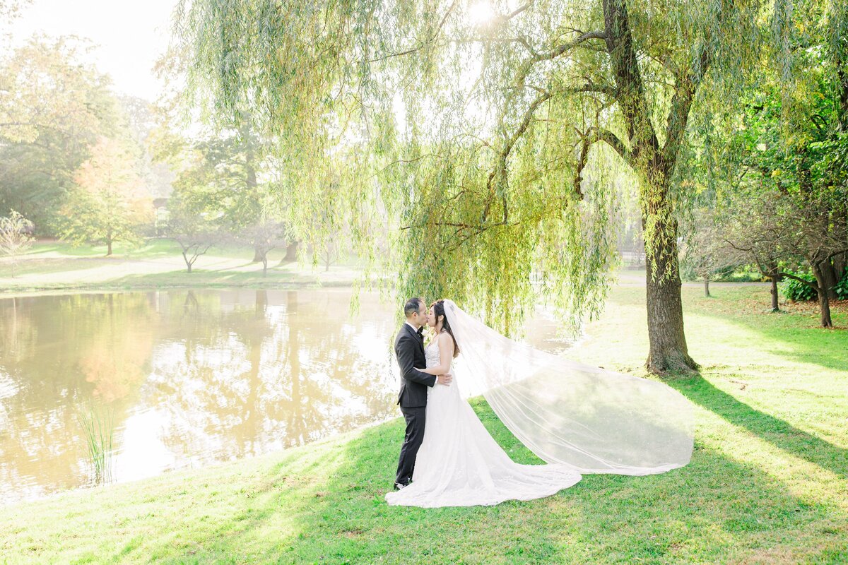 Bride and groom kissing with veils blowing in the breeze during their timeless Boston wedding