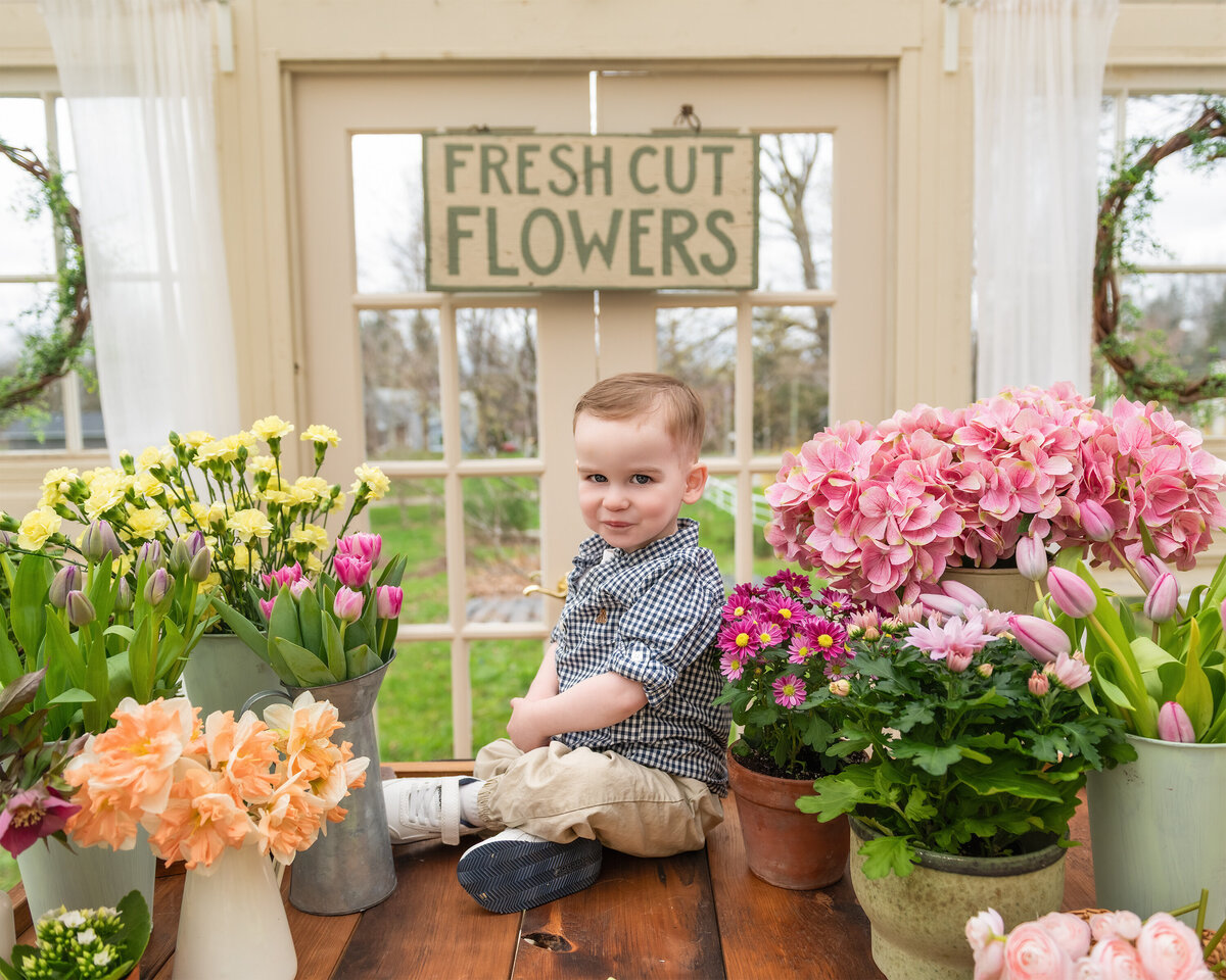 Spring greenhouse portrait of a child surrounded by flowers in a All Who Wander Flower Farm in Dundas Ontario floral market setup