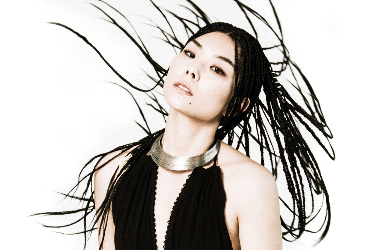 Musician portrait female Masumi tossing braided hair while looking at camera against white backdrop