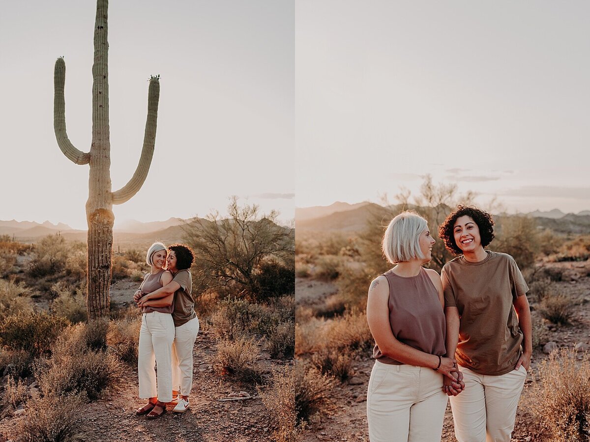 two women cuddle next to a saguaro cactus