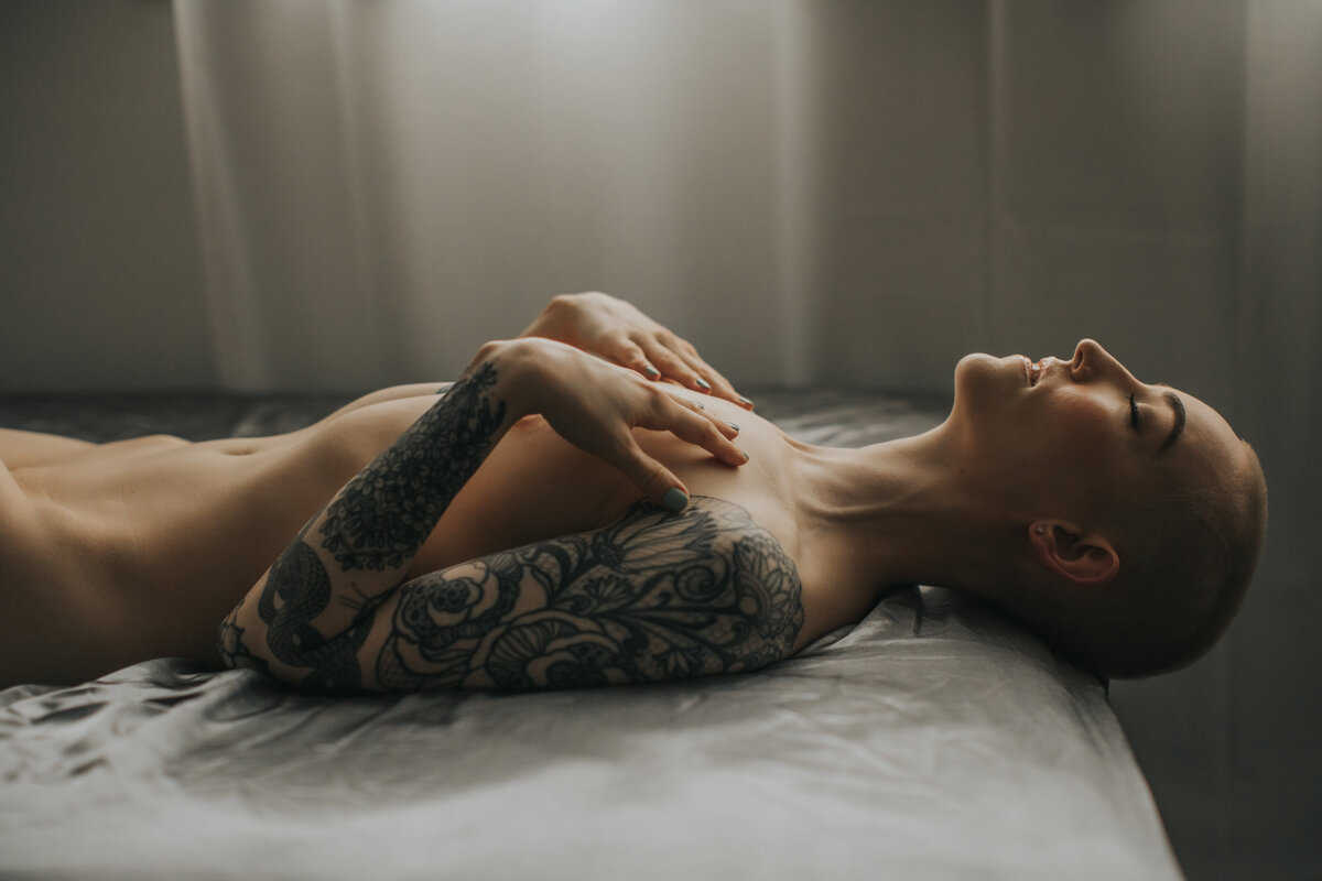 tattoed female laying on a bed