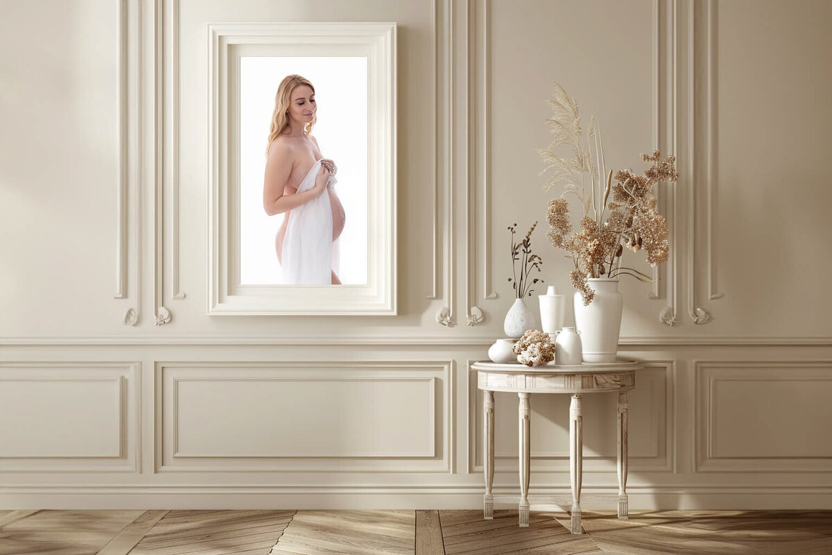 beige room with a framed photo of a pregnant woman at her Burlington, Ontario in studio maternity photography session