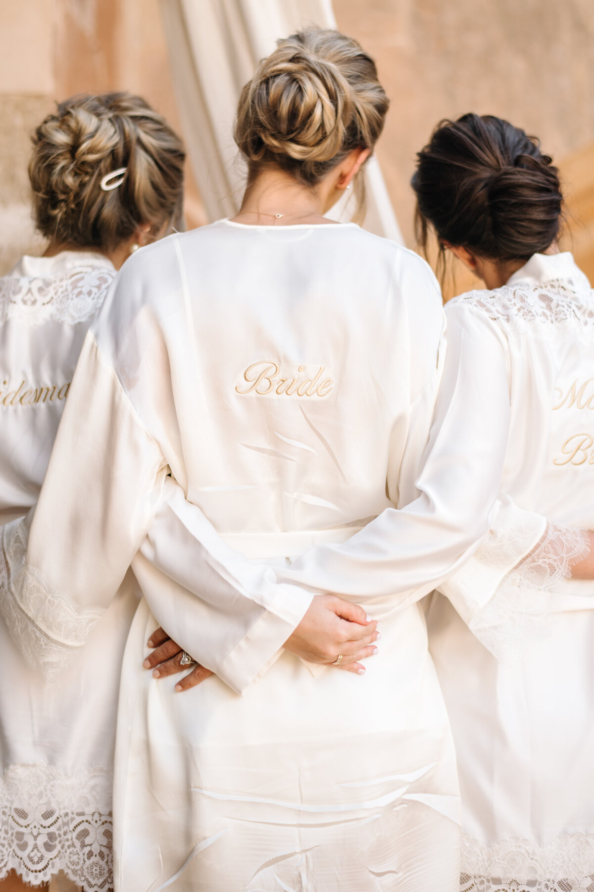 bride and bridesmaids with custom wedding day getting ready robes in white satin