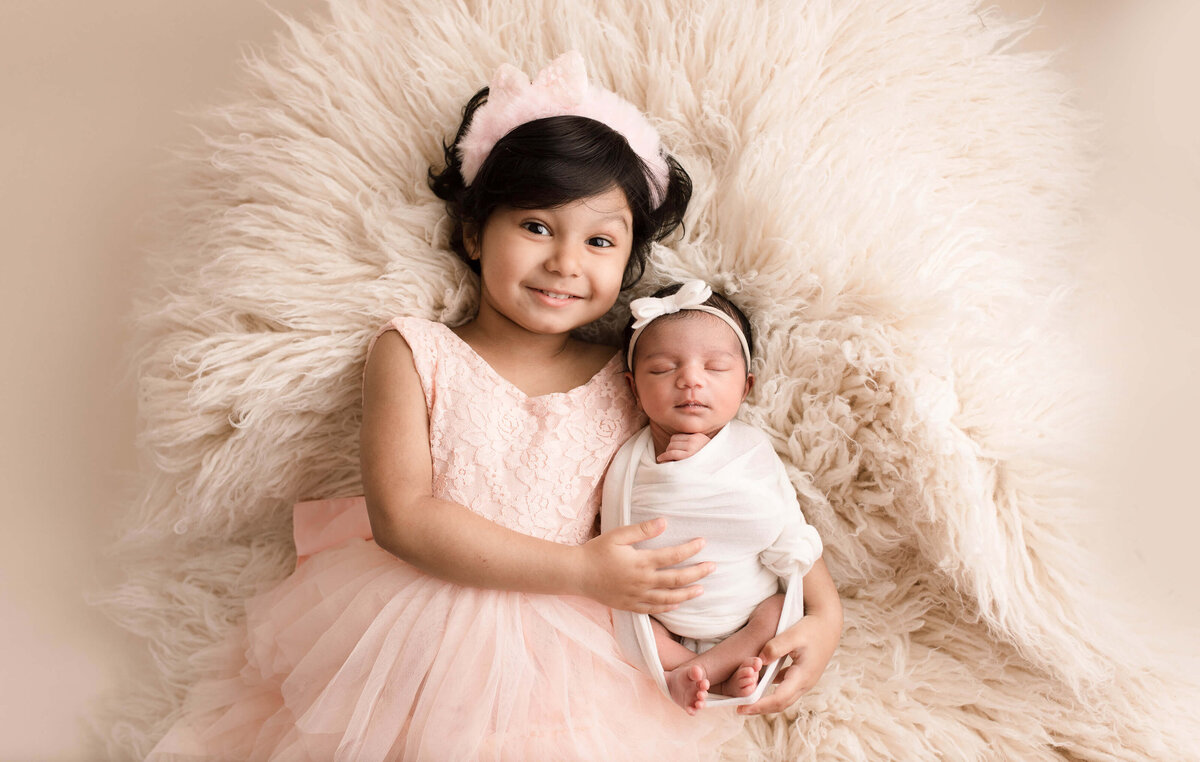 Beautiful sisters in a cream swaddle and pinkn dress