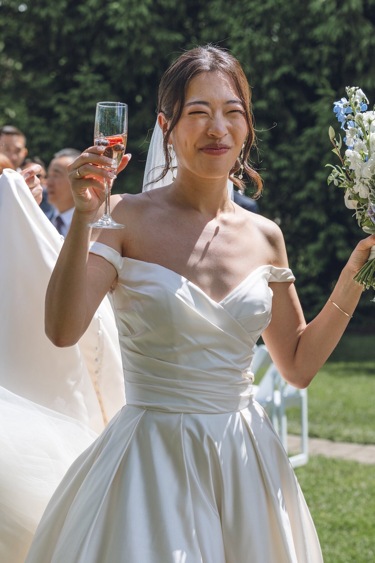 Bride holding champagne and laughing during cocktail hour