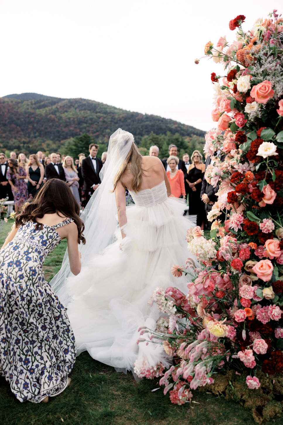 adirondack-mountain-wedding-24-bride-under-floral-arch-during-ceremony,-captured-candidly-at-adirondack-mountain-wedding-jenny-fu-studio