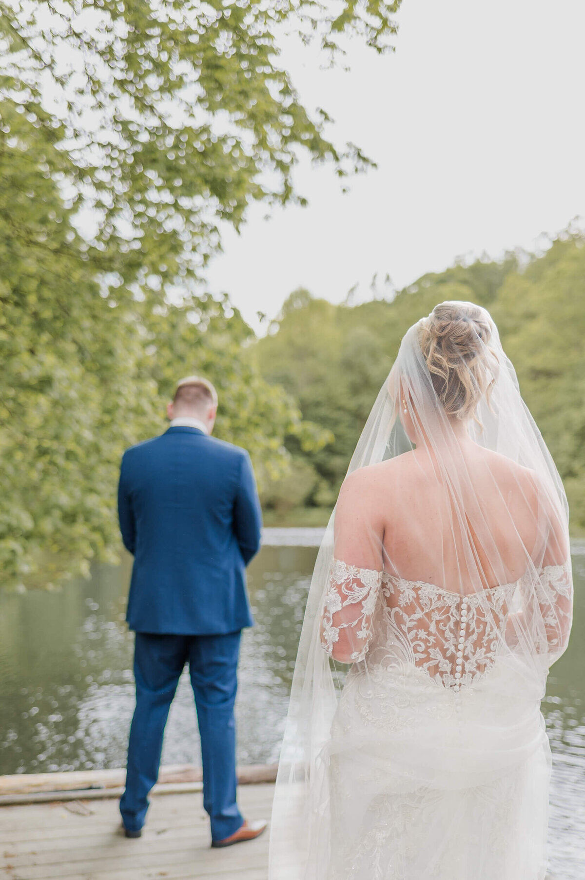 Bride walks toward groom for their first look by the water, captured by a timeless Pittsburgh wedding photographer. 