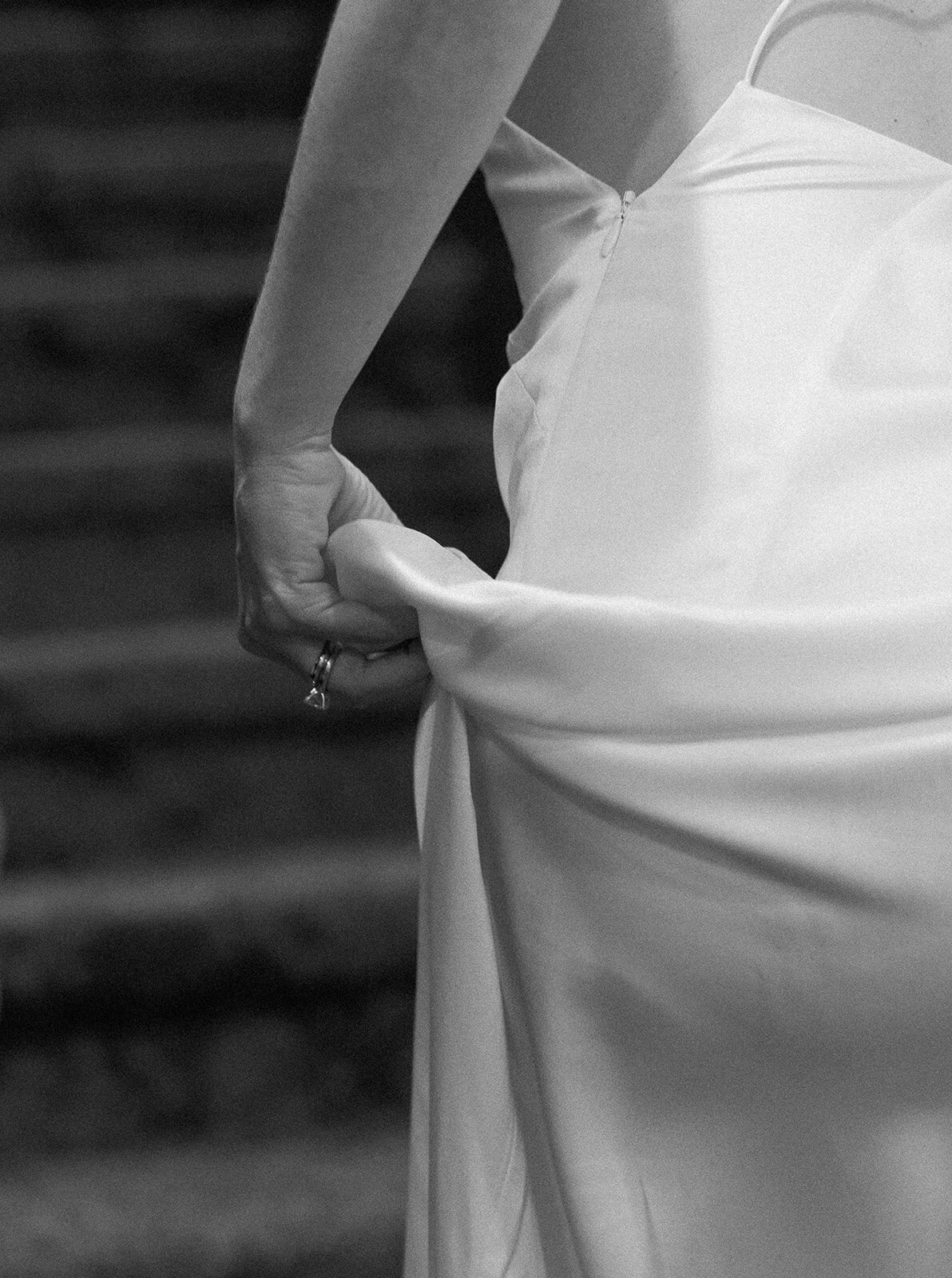 A delicate moment as Minette lifts her gown, revealing intricate details of her wedding dress. Islamorada wedding photography by Claudia Amalia.