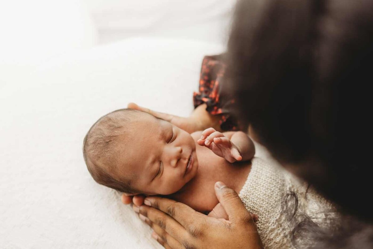 Ruua Hamdan Photography (UK): A baby with dark hair is wrapped in a white blanket.