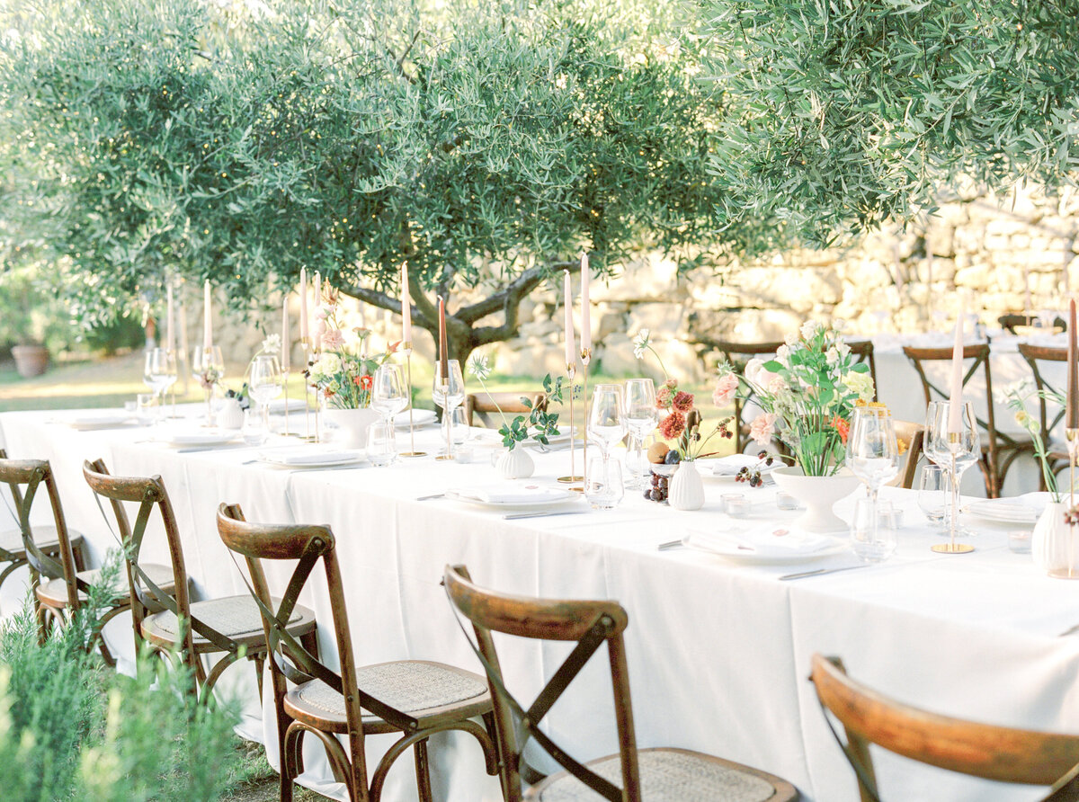 Film photograph of wedding reception tables and wooden chairs among olive trees photographed by Italy wedding photographer at Villa Montanare Tuscany wedding
