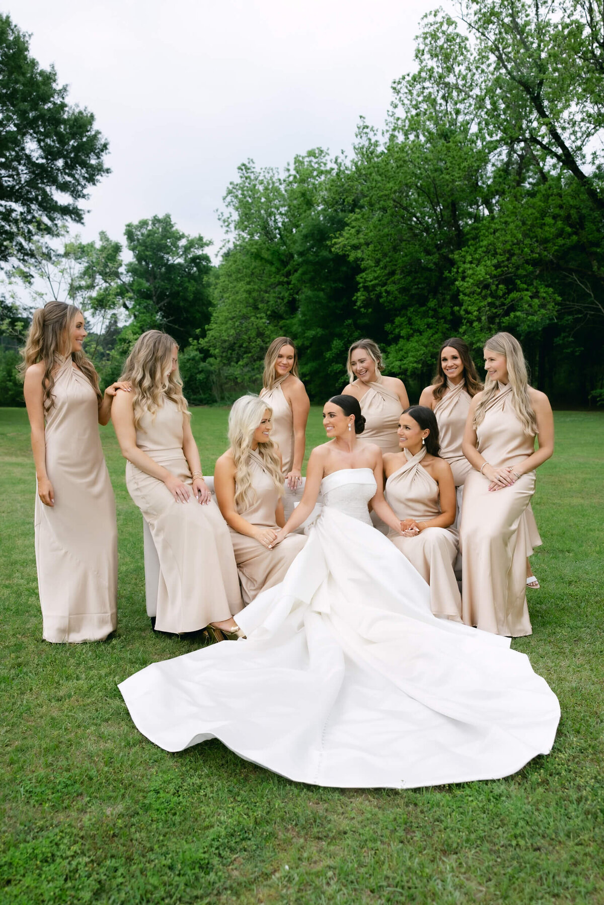 A wedding day portrait photo of the bride in her white wedding dress surrounded by her bridesmaids