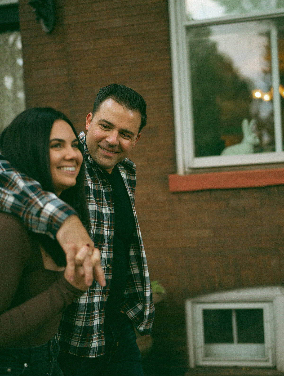Man looking lovingly at his fiancée as she holds his shoulder from behind during a candid engagement session