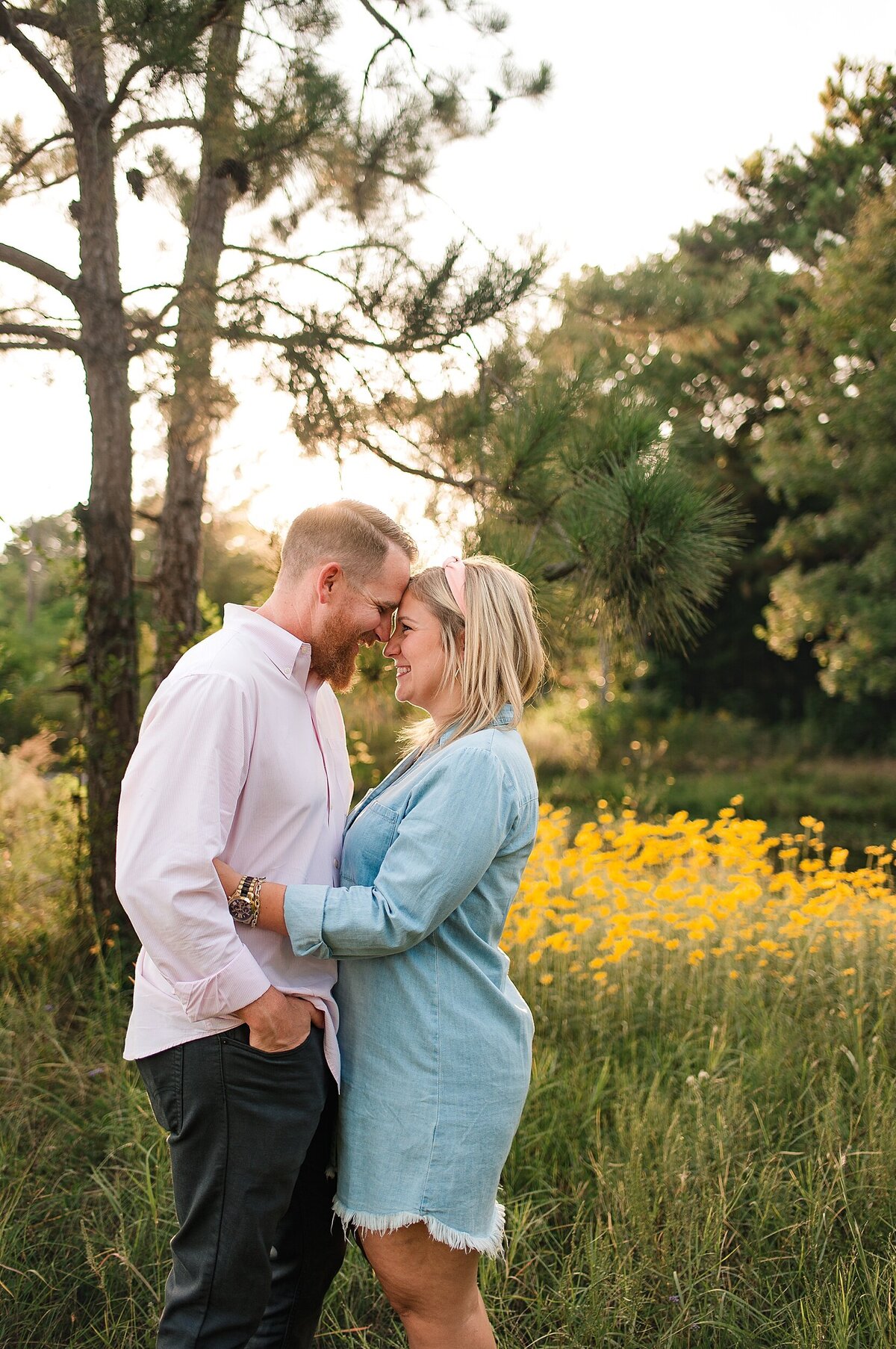 Couple cudding in front of yellow flowers in a field by Cypress Family PhotographerCypress Family Photographer