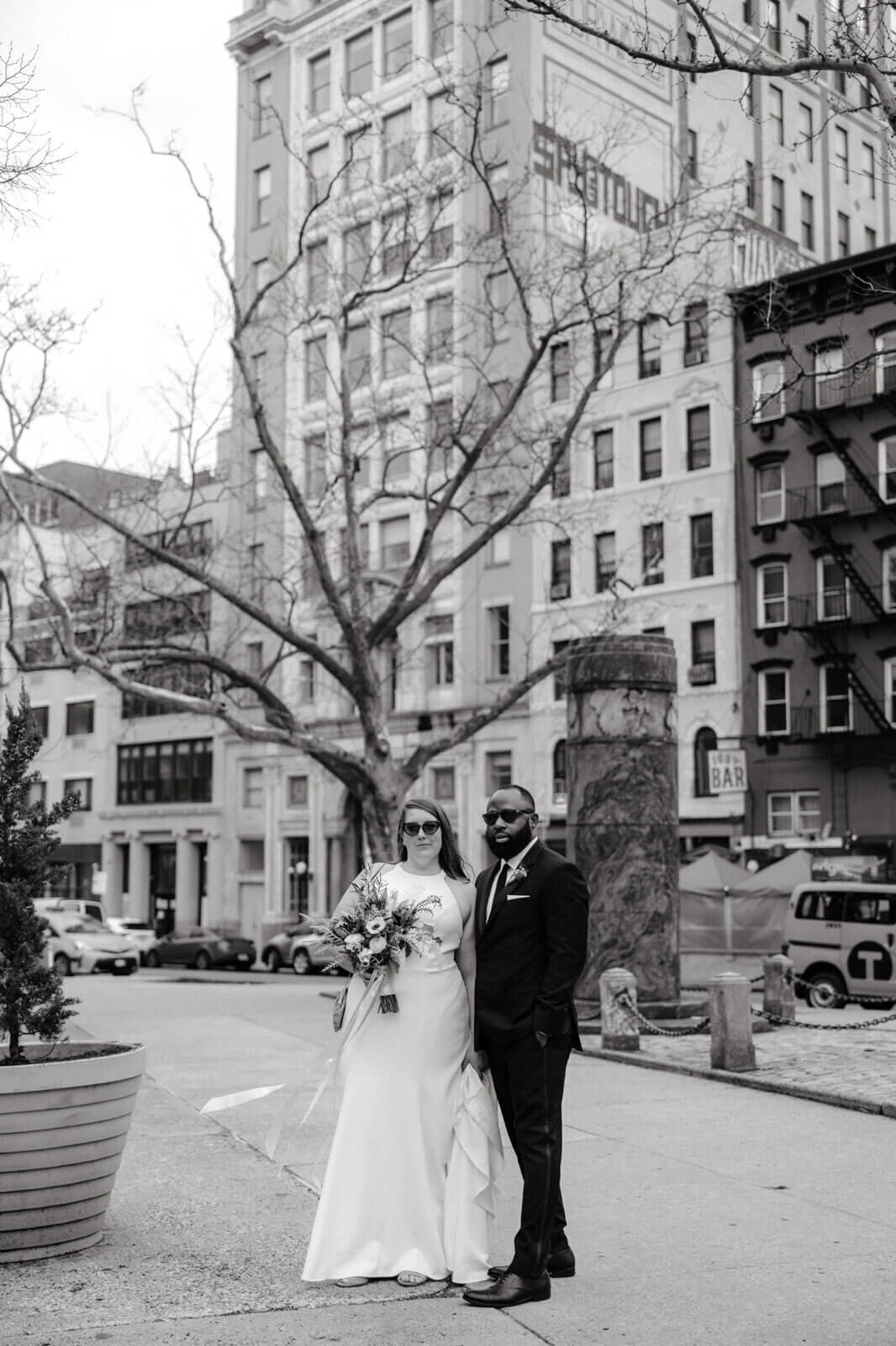 Black and white photo of the bride and the groom standing in front of some buildings in New York City.