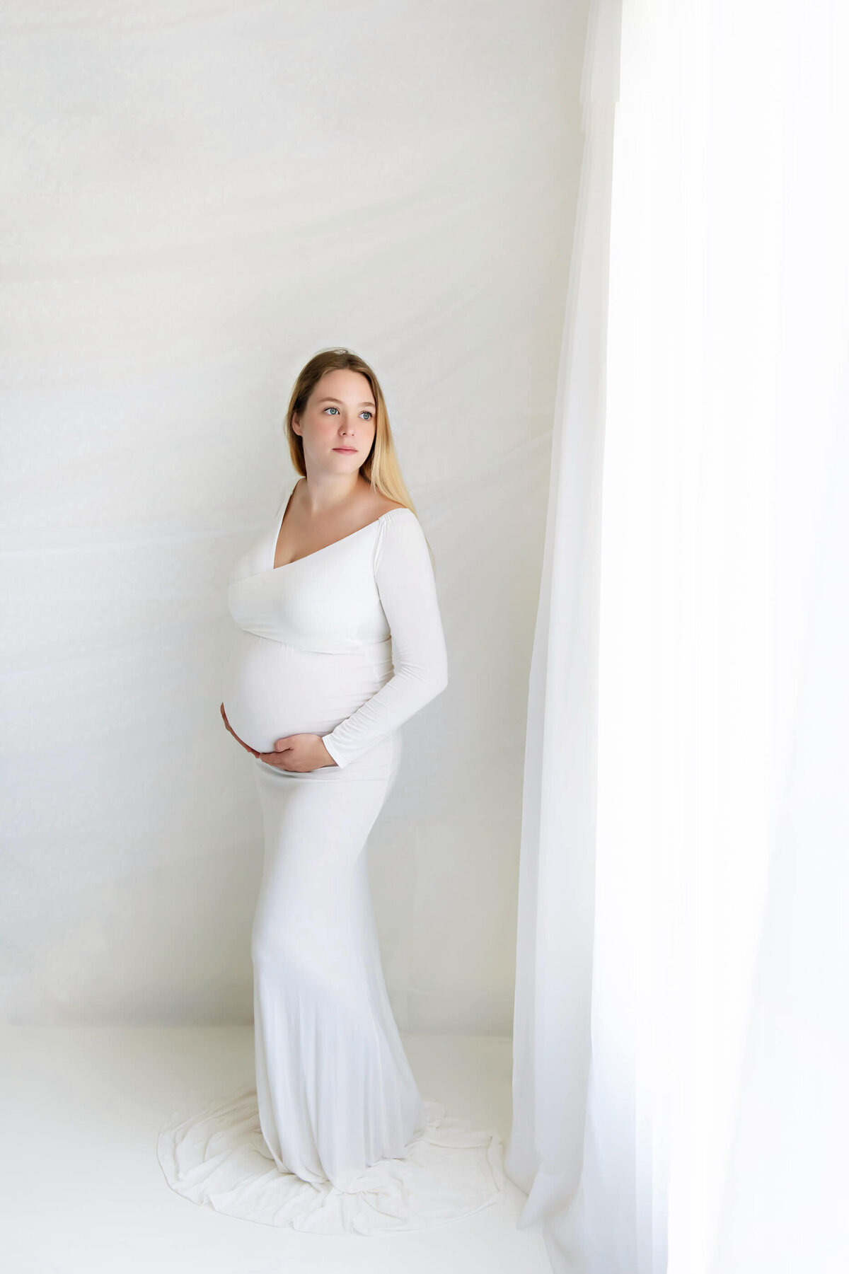 pregnant woman wearing a white maternity dress in studio maternity photography session in Burlington, ON