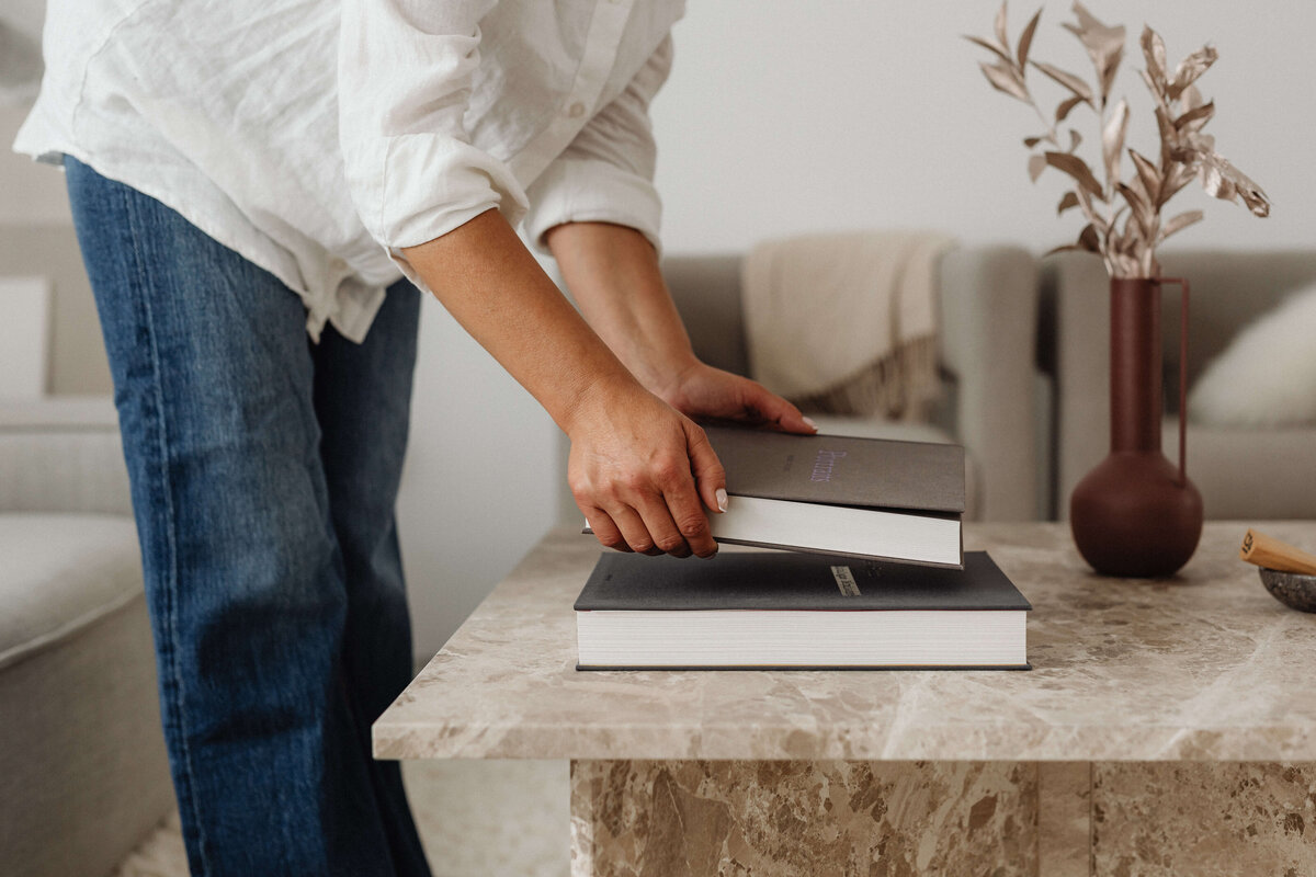 Calm professional woman placing books on table—reflecting aligned, intentional career choices and identity-based coaching