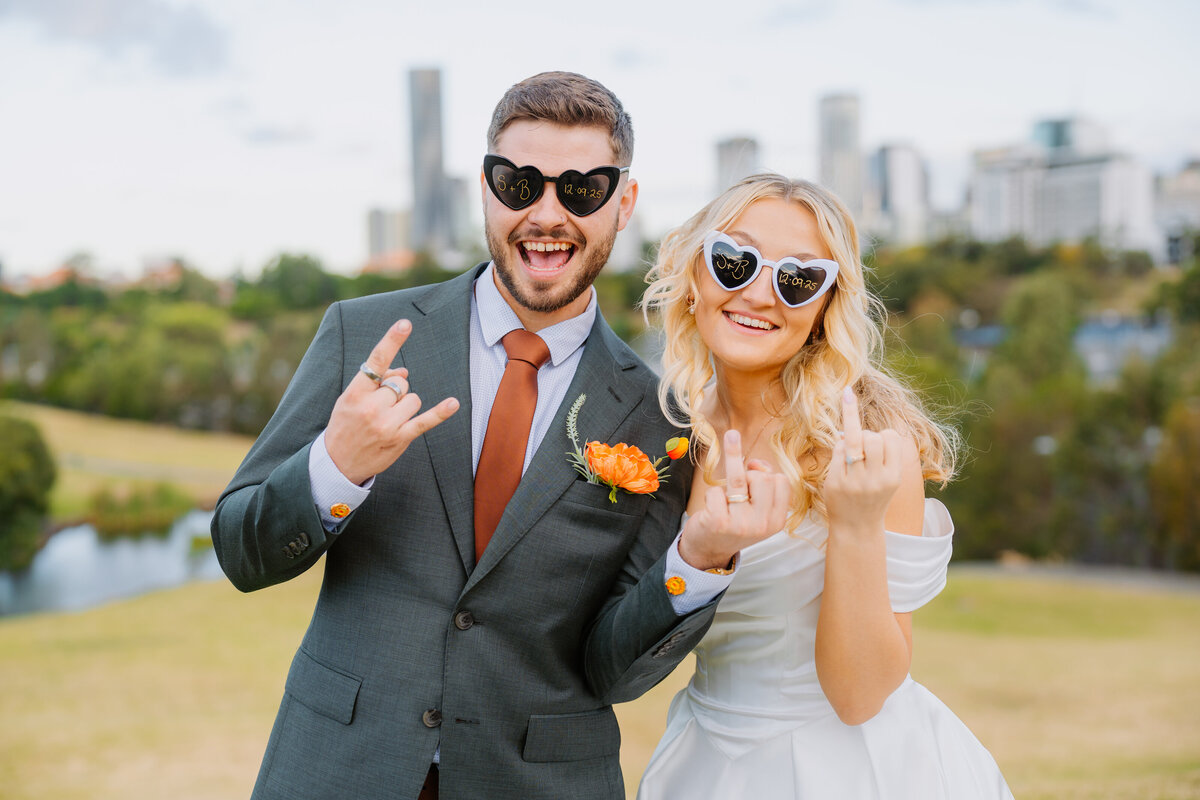 Newly wedded couple showing off their wedding rings with the city in the backdrop.